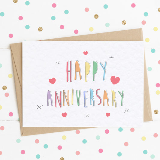 A cute A6 anniversary card with a colourful rainbow text message saying "Happy Anniversary" surrounded by complimenting hearts and x kisses.
