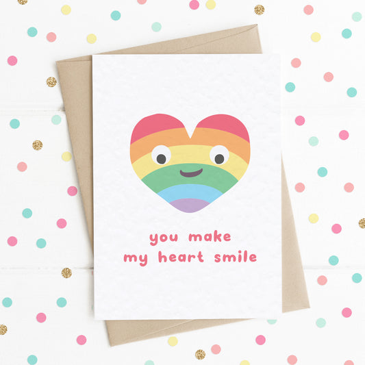 A cute A6 love card with a colourful smiling rainbow heart and a message saying "You Make My Heart Smile".
