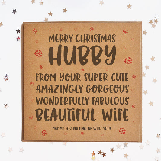 A funny Christmas card for the husband, in festive colours and a message saying "MERRY CHRISTMAS HUBBY! FROM YOUR SUPER CUTE, AMAZINGLY GORGEOUS, WONDERFULLY FABULOUS BEAUTIFUL WIFE! YAY ME FOR PUTTING UP WITH YOU!"