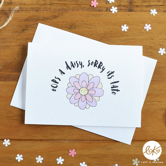 An A6 size card, with a cute smiling happy flower design, with the message "Oops A Daisy, Sorry It's Late".
