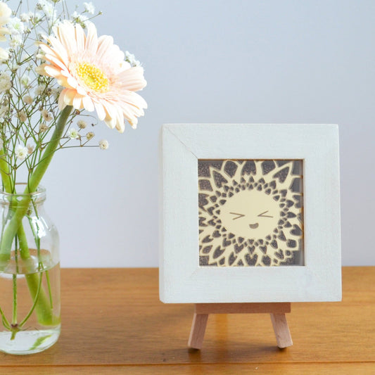 A cute gold mirror acrylic laser cut smiling happy flower, with a gold glitter background, in a rustic white wooden box frame. This design is Sunny Sunflower.