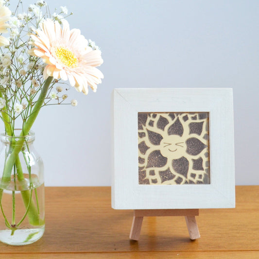 A cute gold mirror acrylic laser cut smiling happy flower, with a gold glitter background, in a rustic white wooden box frame. This design is Dorothy Dahlia.