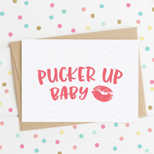 A funny love/Valentine's card with  a red lipstick mark and message in red saying "Pucker Up Baby".