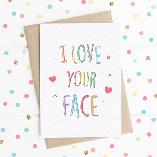 A fun colourful rainbow type A6 size card with the message "I Love Your Face" surrounded by a few hearts and x kisses.
