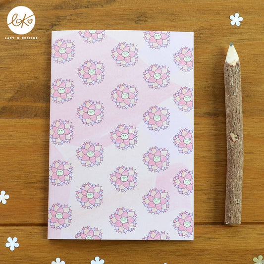 A cute A6 size notebook with a smiling happy flower design. The characters name is Dorothy Dahlia.