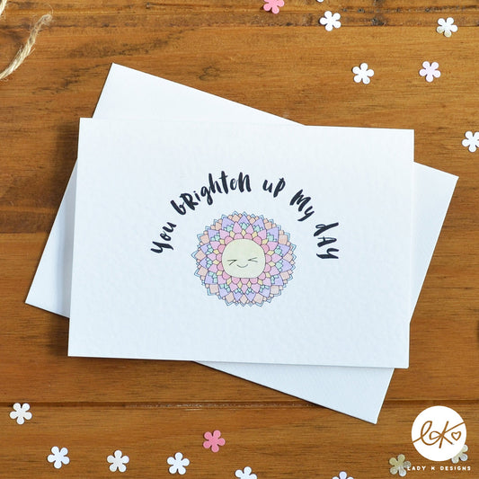 An A6 size card, with a cute smiling happy flower design, with the message "You Brighten Up My Day".