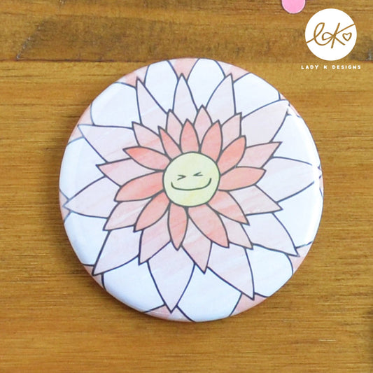 A cute 58mm Pocket Mirror with a smiling happy flower design. The characters name is Ginny Gerbera.