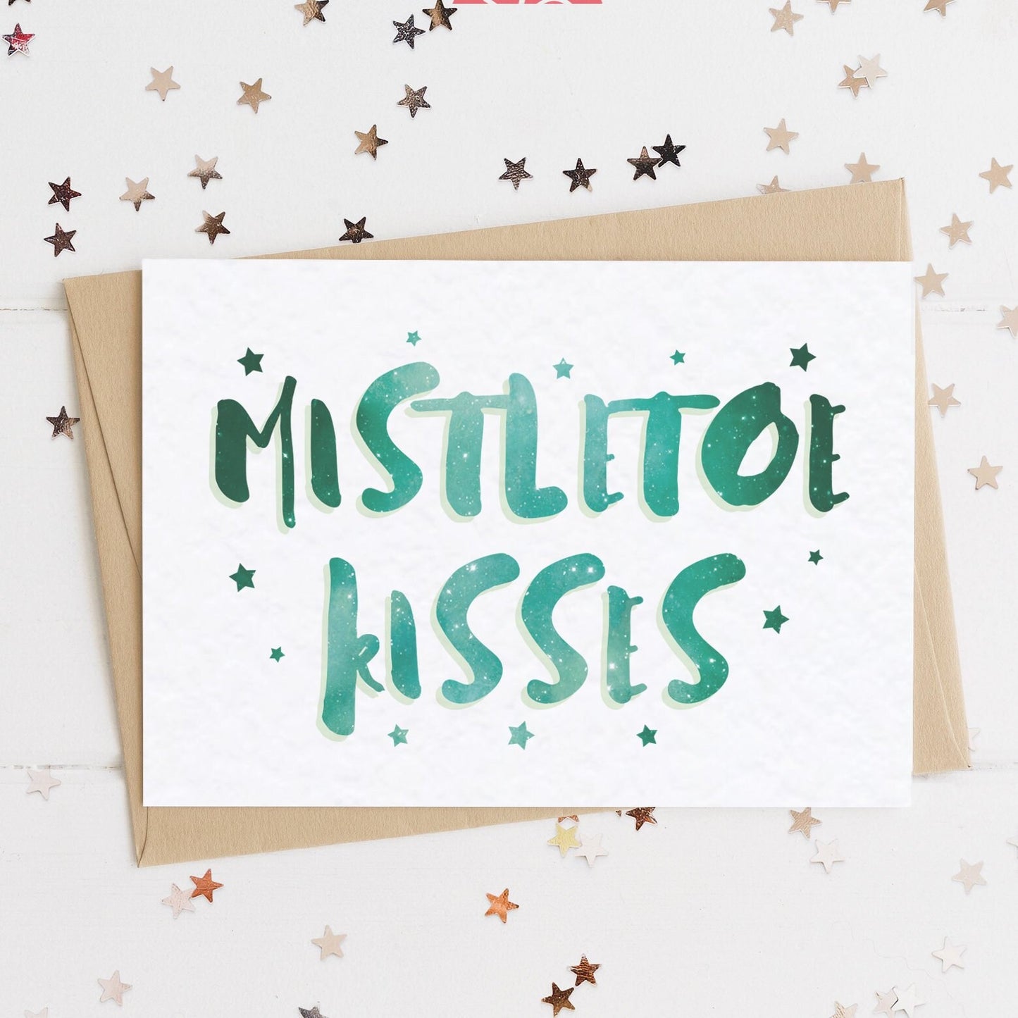 A celestial Christmas card with a stars and text in colours inspired by the northern lights/hygge and the message, "MISTLETOE KISSES".