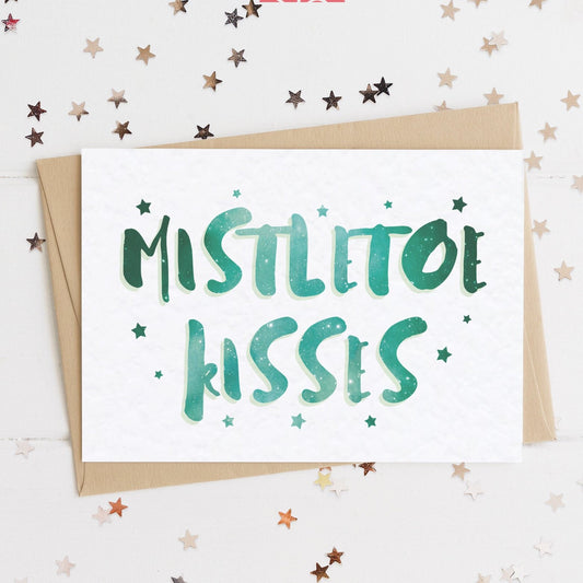 A celestial Christmas card with a stars and text in colours inspired by the northern lights/hygge and the message, "MISTLETOE KISSES".
