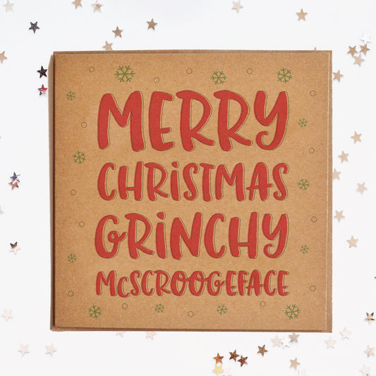 A funny Christmas card in festive colours and the message "Merry Christmas Grinchy McScroogeface" surrounded by decorative snowflakes.