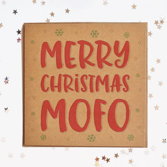 A funny Christmas card in festive colours and the message "Merry Christmas Mofo" surrounded by decorative snowflakes.
