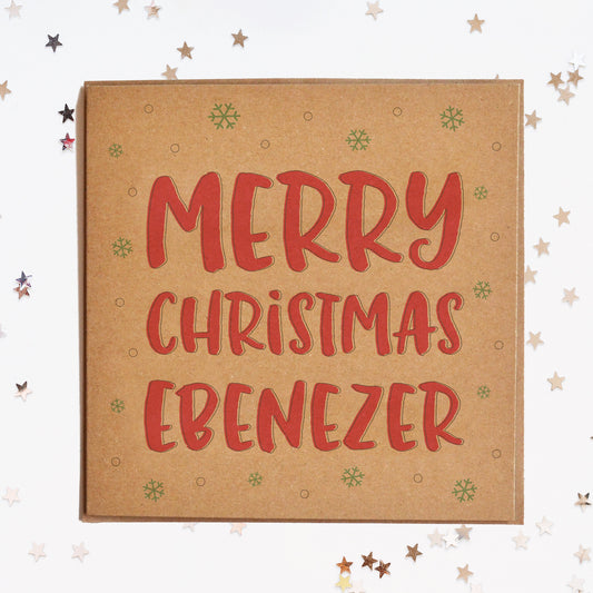 A funny Christmas card in festive colours and the message "Merry Christmas Ebenezer" surrounded by decorative snowflakes.