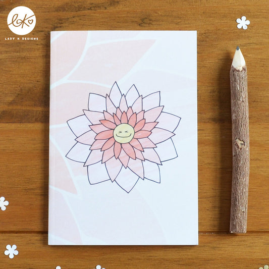 A cute A6 size notebook with a smiling happy flower design. The characters name is Ginny Gerbera.